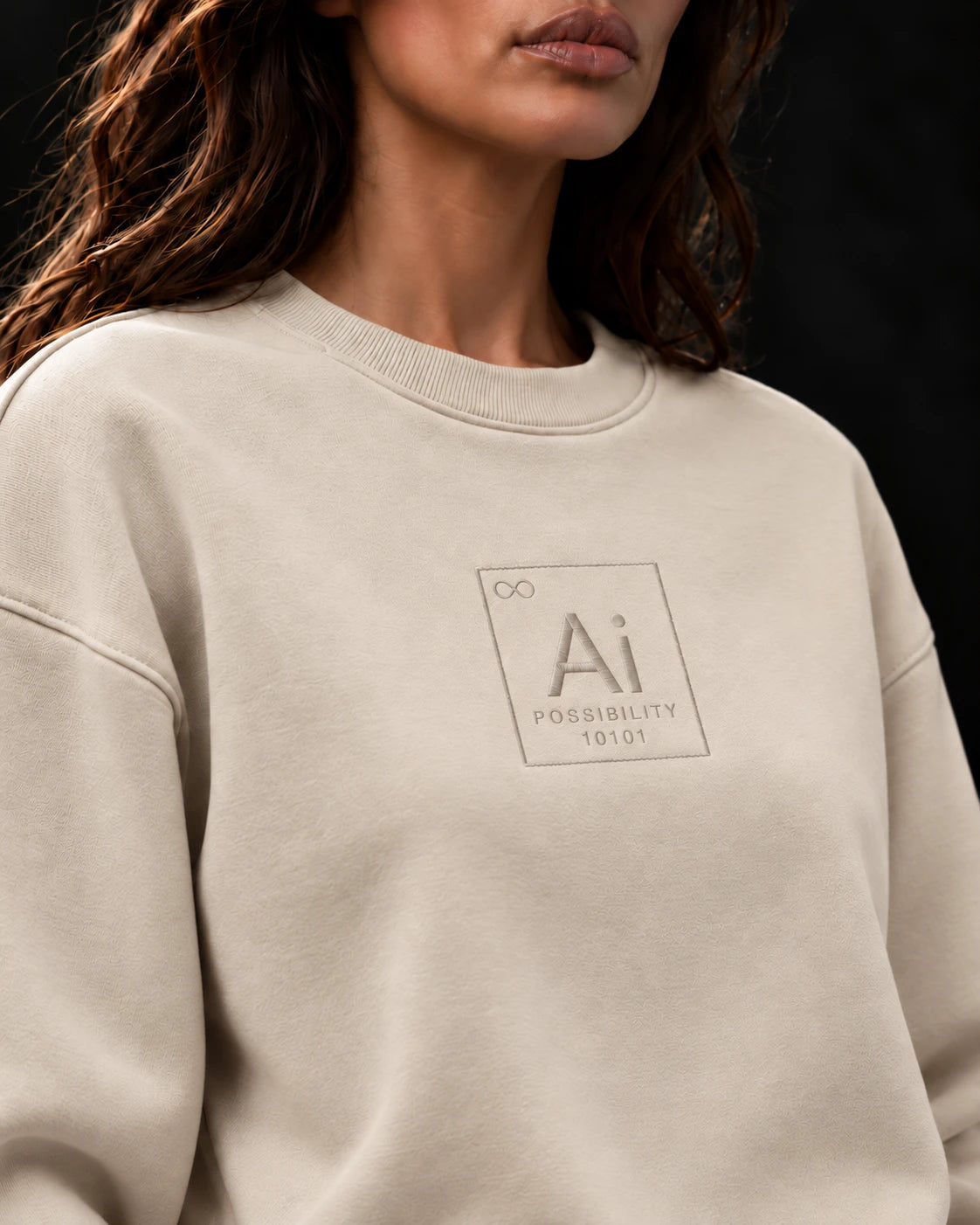 Close-up of the tone-on-tone embroidered Ai + You element tile on the chest of the cream Possibility Crewneck