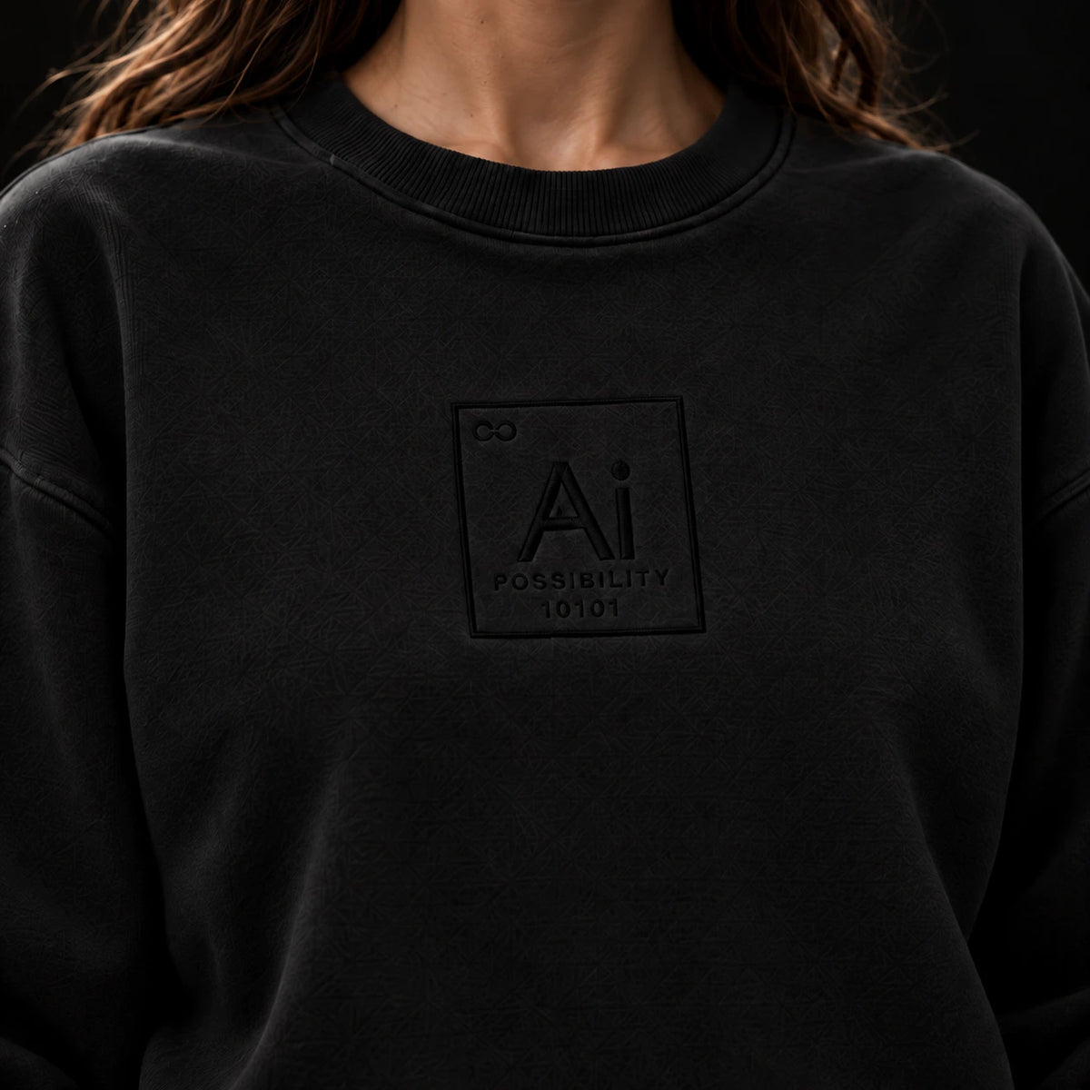 Close-up of the tone-on-tone Ai element mark on the chest of the washed black crewneck