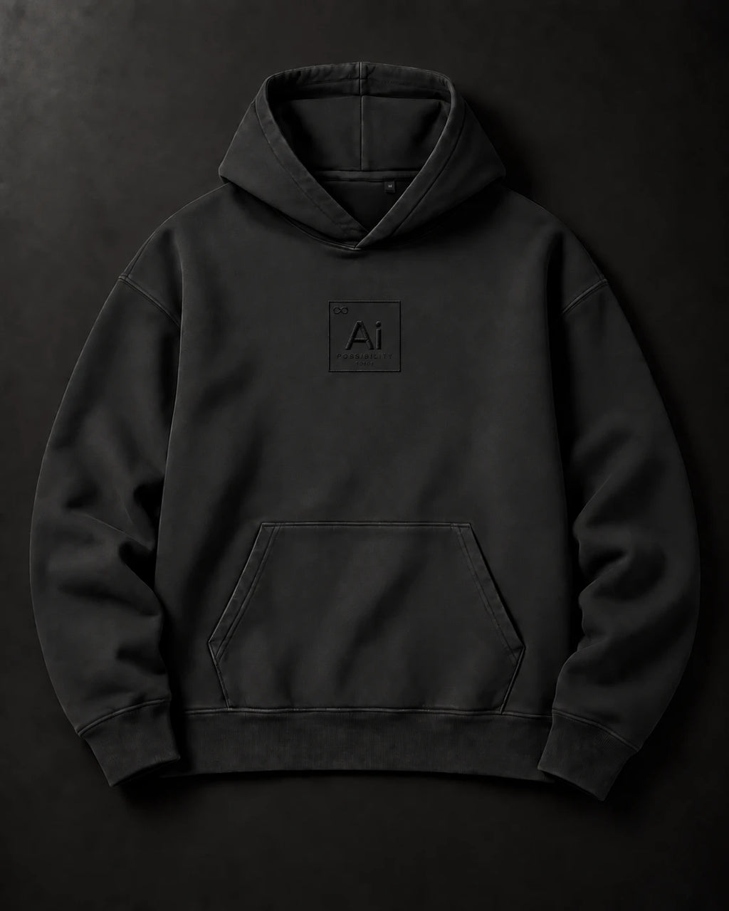 The Possibility Hoodie in washed black laid flat on a charcoal surface