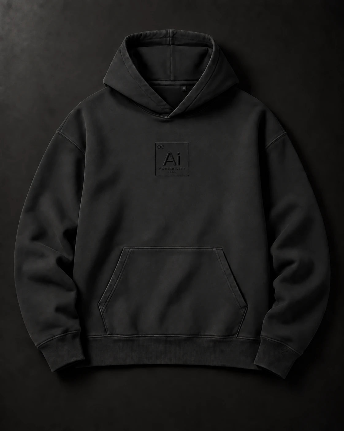 The Possibility Hoodie in washed black laid flat on a charcoal surface