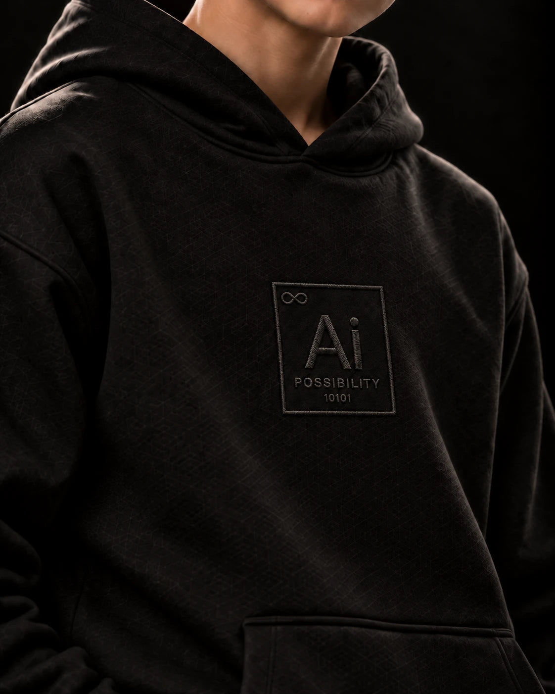 Close-up of the Ai + You element tile on the chest of the black Possibility Youth Hoodie